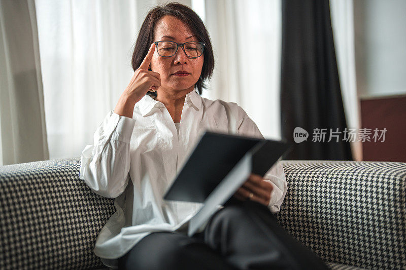 亚洲中年女性专注于使用平板电脑阅读