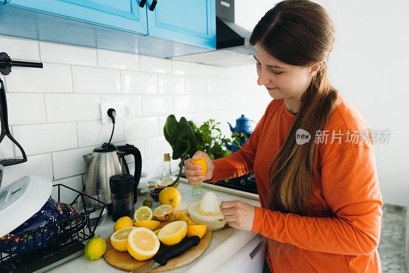 在厨房里用柑橘类水果榨新鲜果汁的妇女