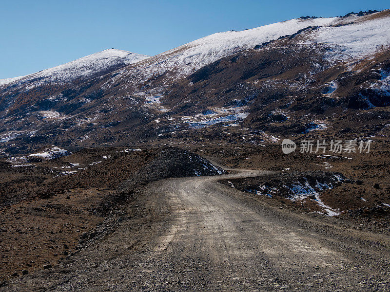 山路越野到一个高山村。积雪覆盖的狭窄山路在雪山的斜坡上。危险的越野驾驶沿着山脉的边缘和陡峭的悬崖。