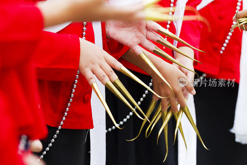 在清迈省，穿着红色衣服的十几岁的泰国朗姆酒舞者伸出金色指甲的双手