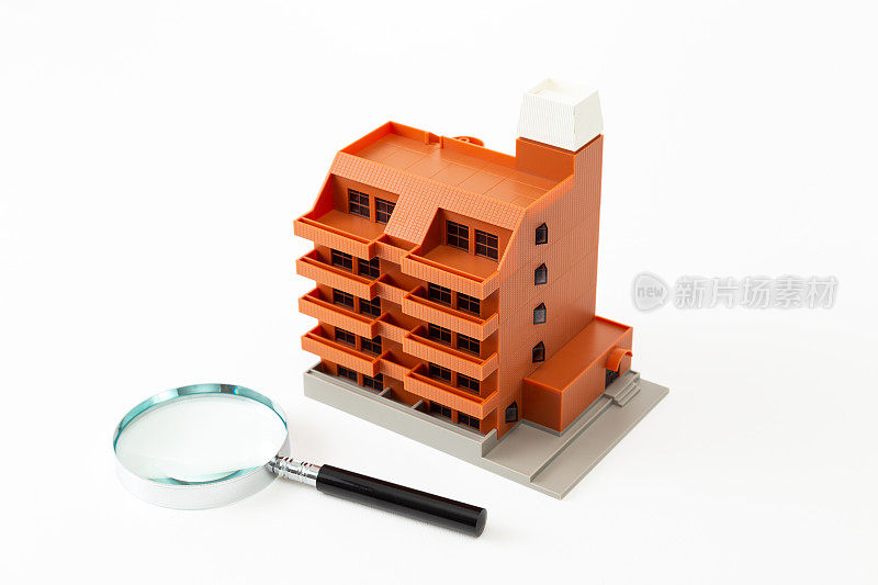 白色背景上的公寓房子模型和放大镜。