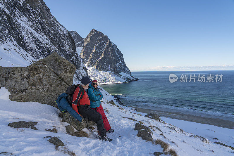 两个人在罗弗敦冬季Kvalvika海滩的山口