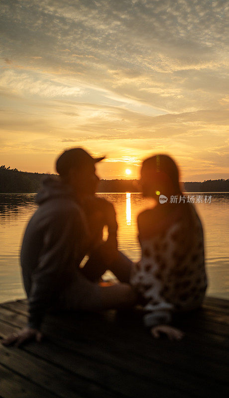 一对浪漫的情侣在码头上放松。在湖上欣赏日落的景色