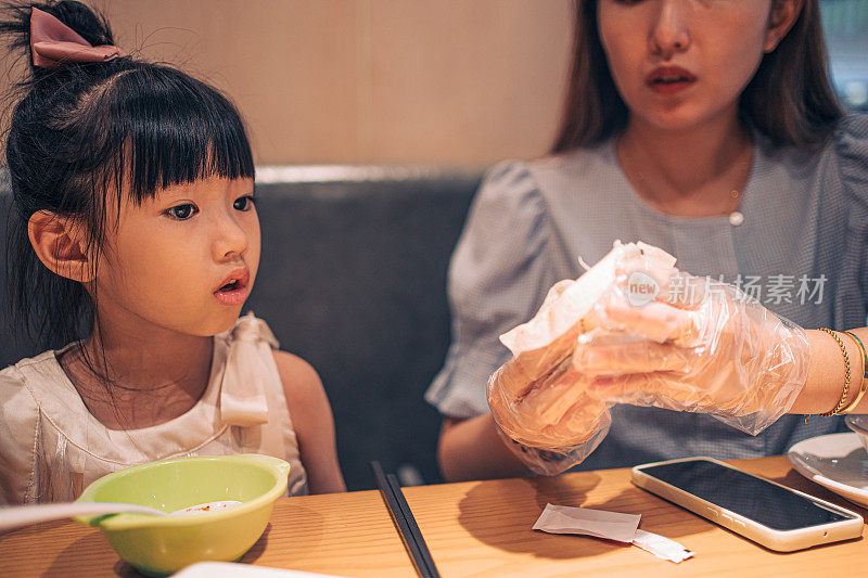 一位母亲在餐馆里帮女儿挑选食物