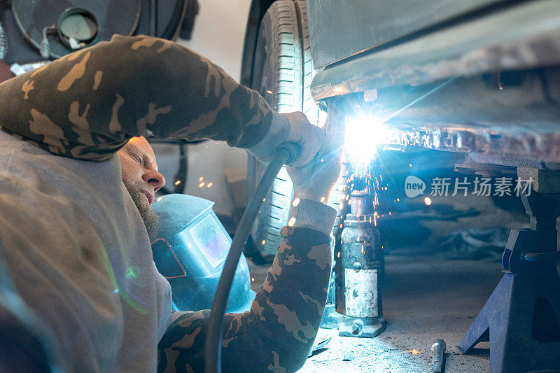机械师用电焊机修理汽车门阀。