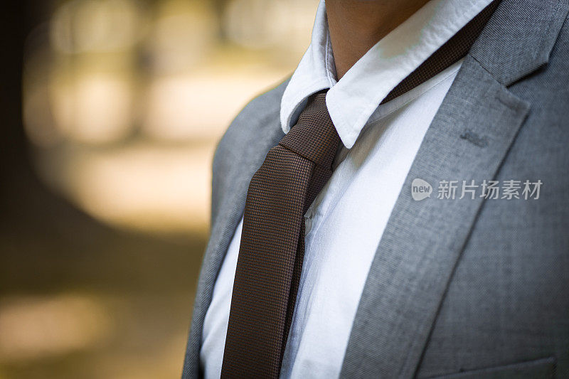 难以辨认的年轻商人，穿着正装，正在整理领带