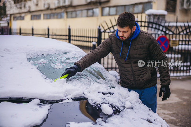 年轻人正在清除汽车上的积雪