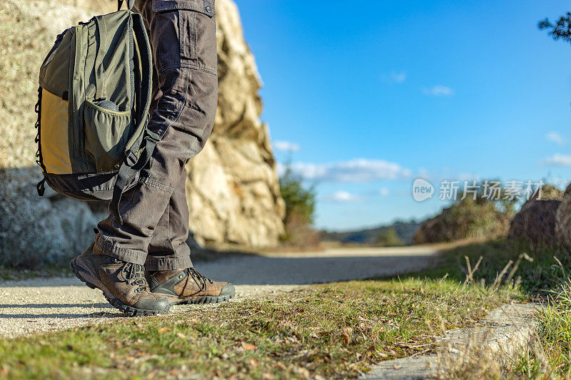 一名男性徒步旅行者沿着人行道行走的俯视图。穿着山裤和靴子，背着背包。