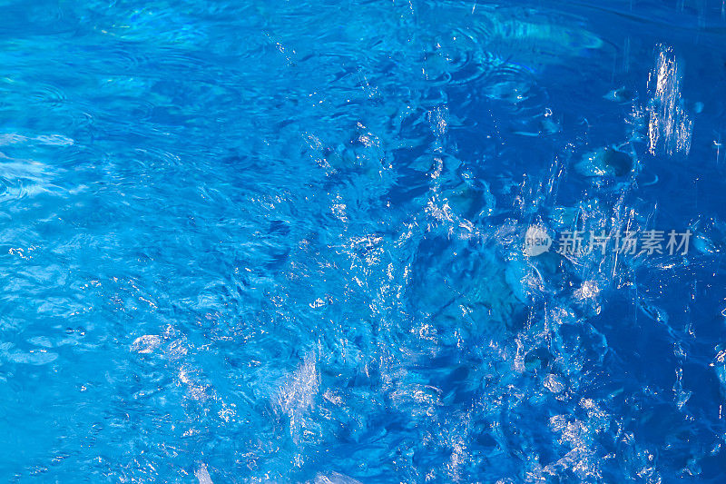 游泳池蓝绿色的水面，太阳在蓝色的水面上反射