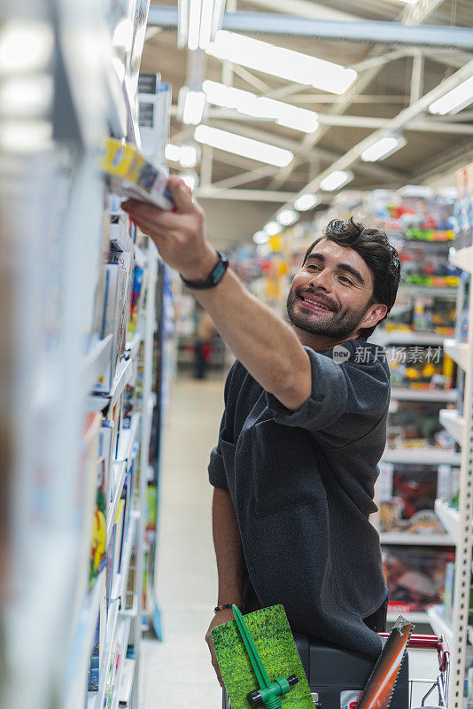 一个拉丁裔男子推着购物车在一家连锁店里寻找家里需要的重要物品