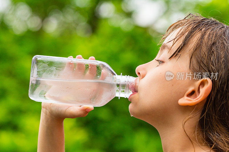 孩子从透明塑料瓶中饮用干净的自来水