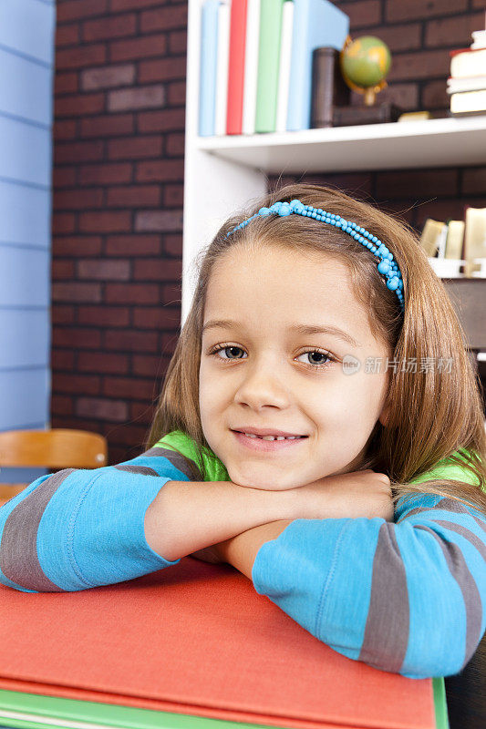 小学生，7-8岁，女孩双臂交叉叠着图书馆的书