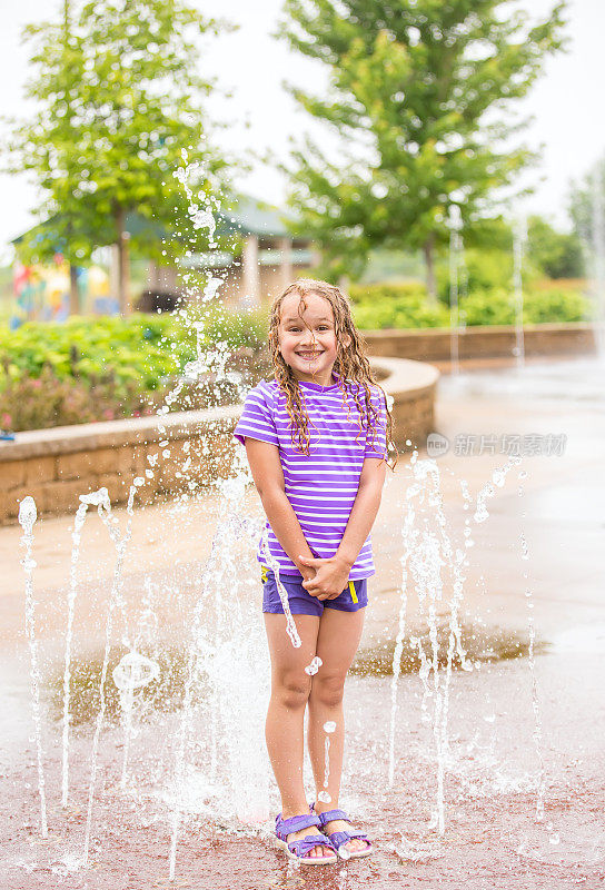 女孩站在喷水池在夏天的一天
