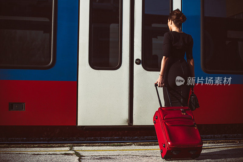 优雅的女人提着行李箱上了火车