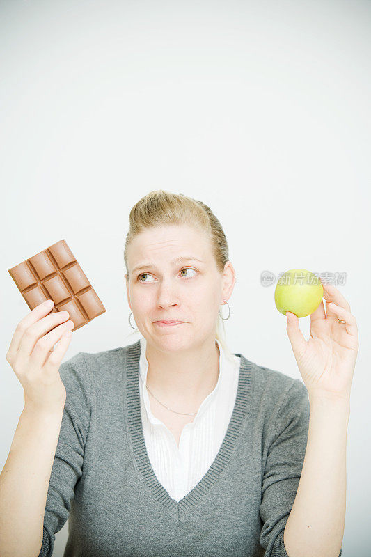 拿着巧克力和苹果的女人的饮食选择