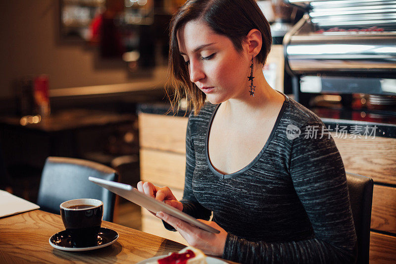 一个年轻女子在咖啡店里用平板电脑工作