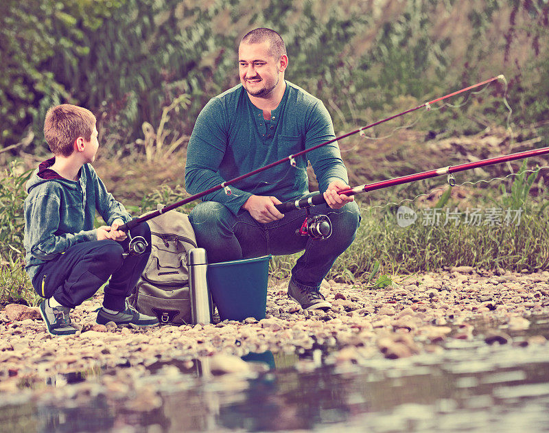 父亲和儿子拿着钓竿钓鱼的肖像