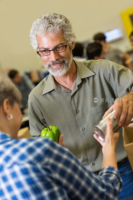 老人自愿在食品银行为健康的人捐赠食物
