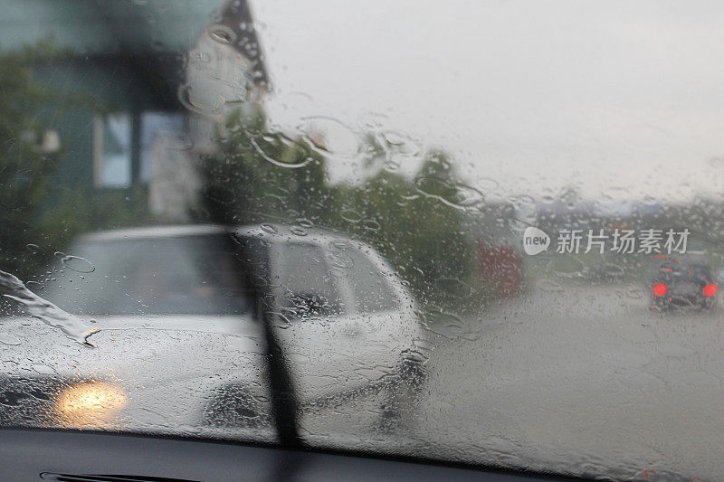 在雨天驾驶时，雨滴落在汽车的挡风玻璃上。
