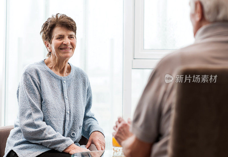 快乐的老女人在家里和她的丈夫聊天。