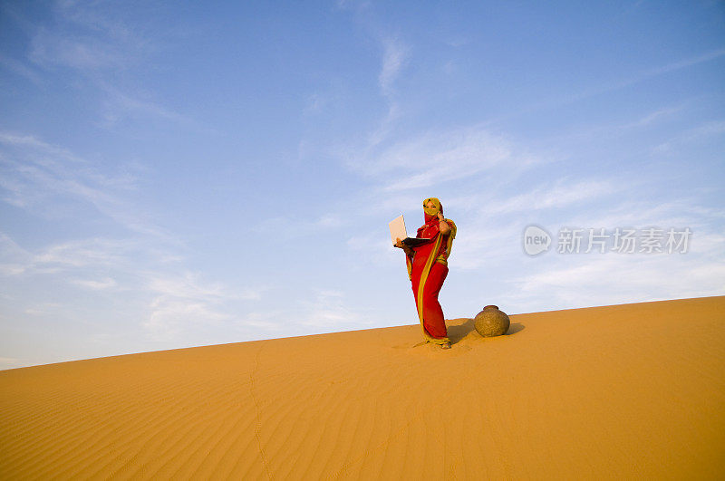 亚洲女人在沙漠中使用笔记本电脑