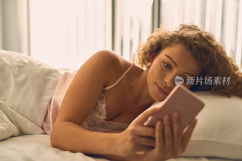年轻漂亮的女人在床上玩手机
