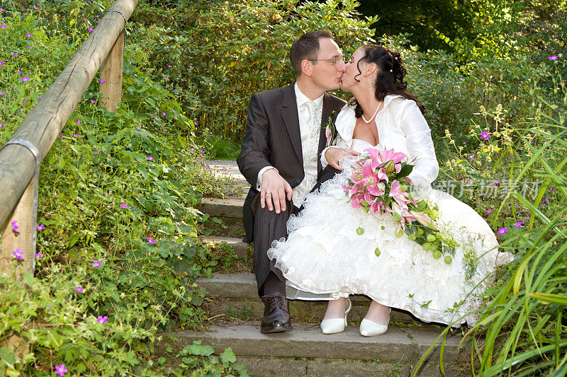 幸福的新娘和新郎坐在楼梯上接吻