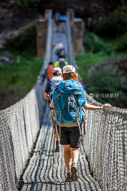 尼泊尔Annapurna徒步旅行者穿过一座吊桥