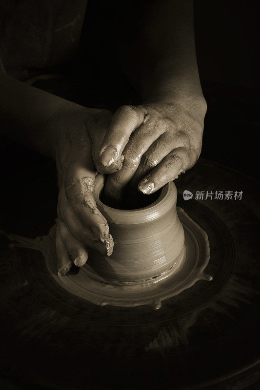 黑暗中，双手在陶艺轮上塑造粘土