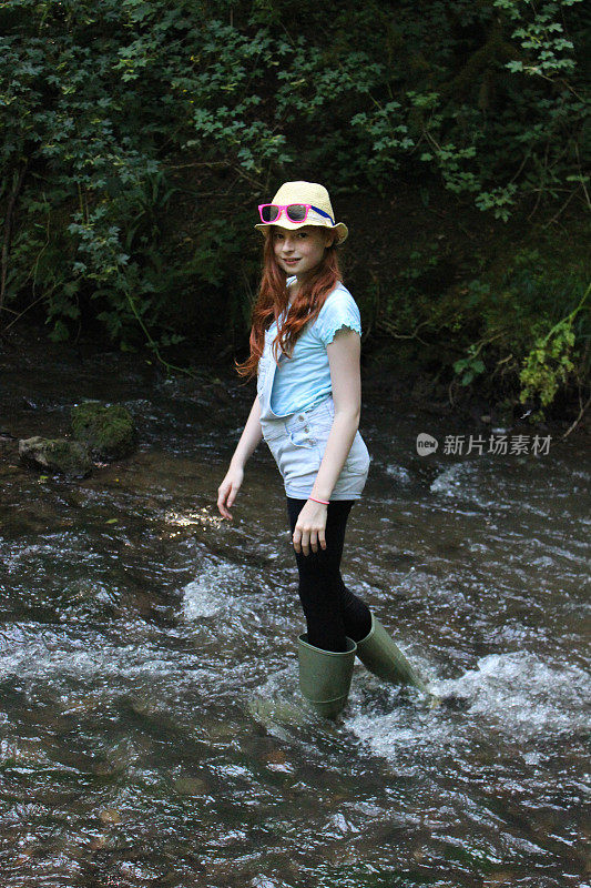 女孩的形象玩耍，划水，溅水，涉水在河流，林地
