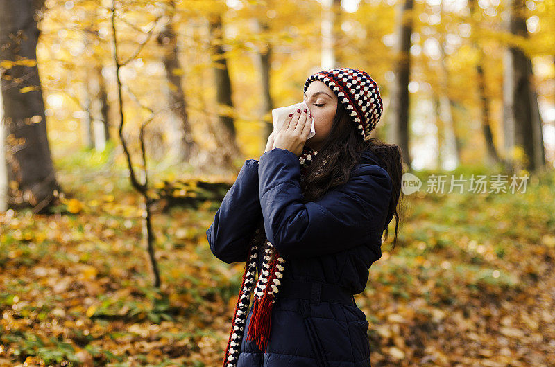 女人在秋天用手帕打喷嚏