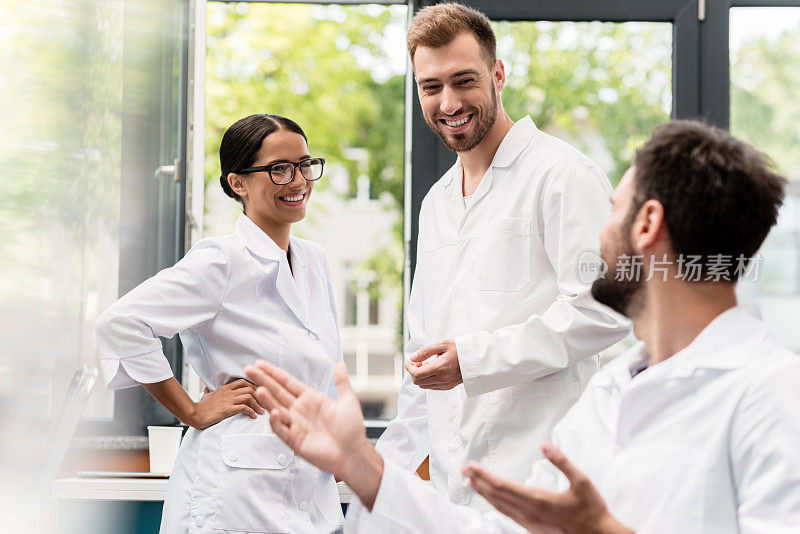一队身穿白大褂的专业科学家在实验室里微笑和交谈