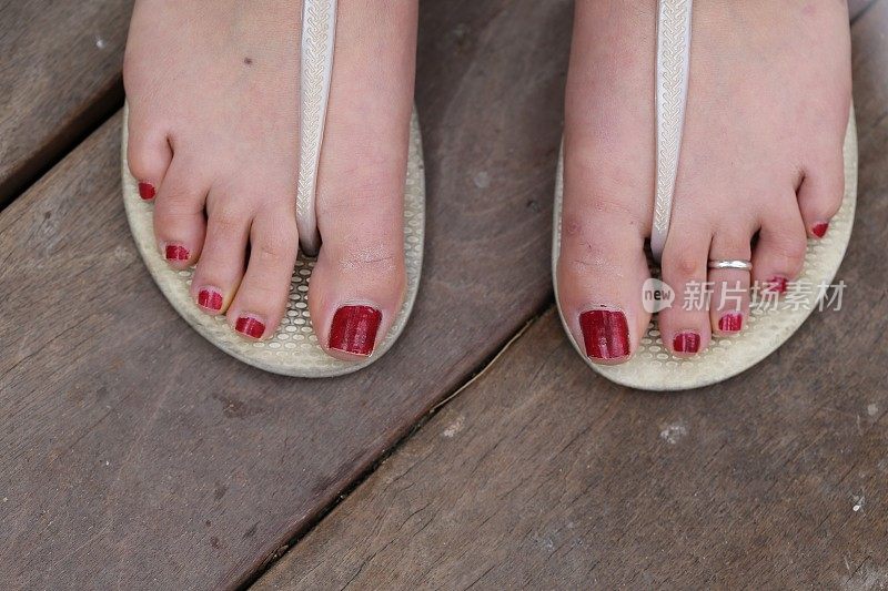 红色脚趾甲的年轻女人的脚。