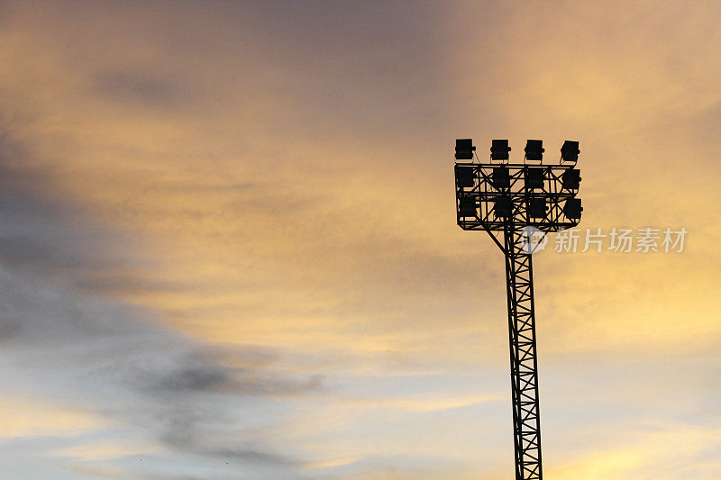 聚光灯在体育场与橙色的天空。