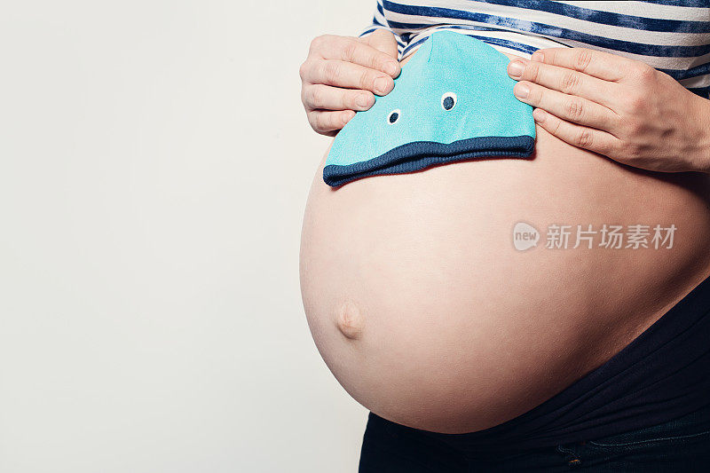 怀孕的女人。女性胃和小蓝帽子的背景与Copyspace