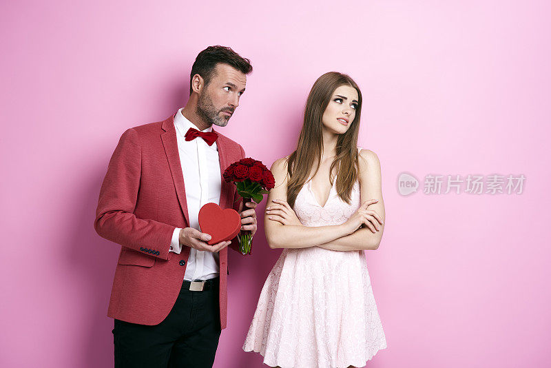 男人捧着一束玫瑰和巧克力盒子向未婚夫道歉
