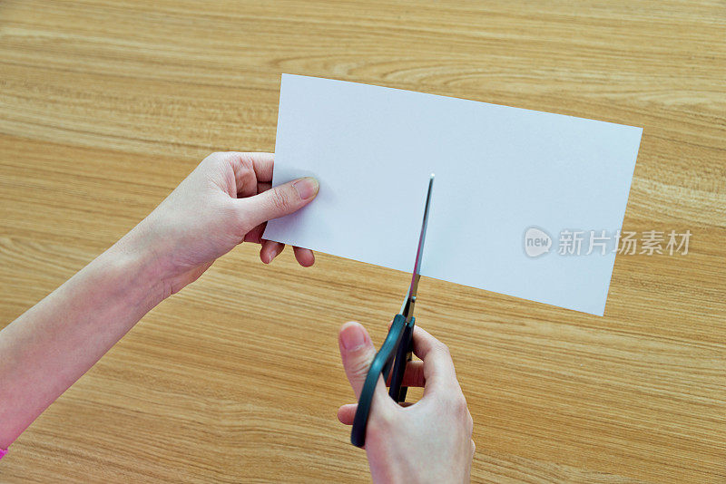 女人用剪刀剪一张白纸
