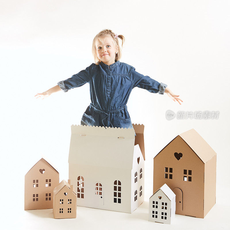 一个小女孩在纸板房子里玩。幸福的概念，人，家庭，孩子，童年，在幼儿园或在家里玩。