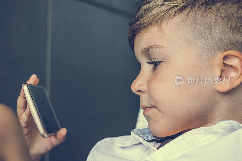 男孩在智能手机上看卡通的特写。
