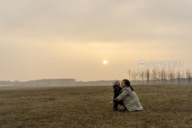 年轻的母亲和婴儿儿子一起在草地上玩