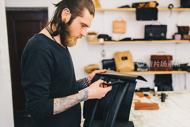 男子检查质量皮革背包。皮革车间皮革背包的工作流程。