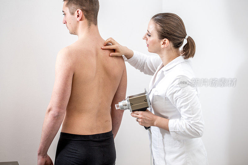 女性皮肤科医生痣映射年轻男子的背部