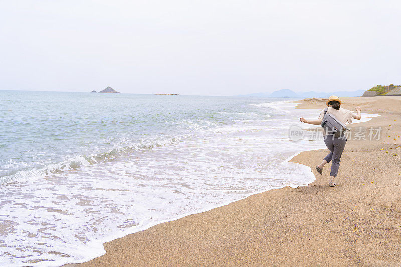 一位女旅行者在海滩上散步