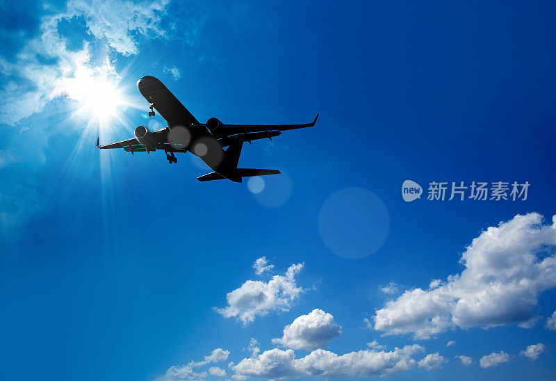 一架飞过阳光灿烂天空的商用飞机的剪影