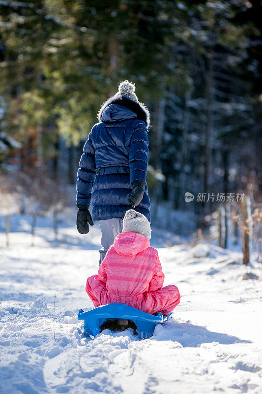母亲和女儿在大自然中享受雪橇