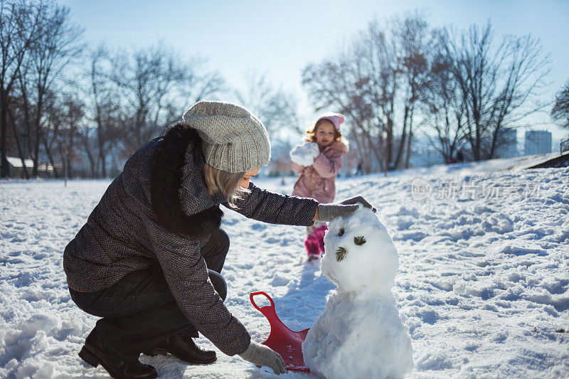 奶奶和孙女在冬天堆雪人