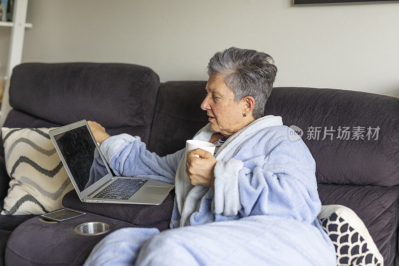 高级女性在家生病时使用笔记本电脑