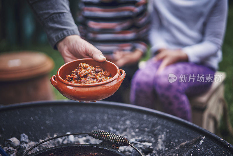 年轻的家庭在户外的篝火前吃辣味牛肉