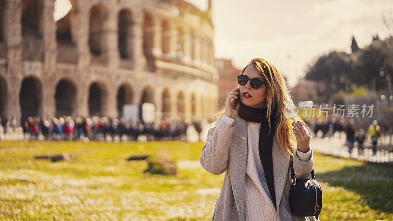 一个金发女人在罗马圆形大剧场前打电话