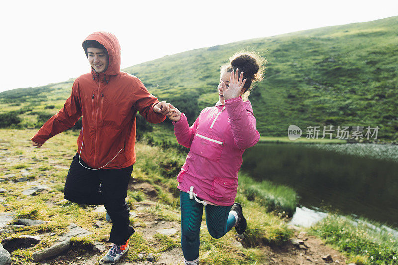 年轻夫妇在美丽的湖附近的山上玩耍